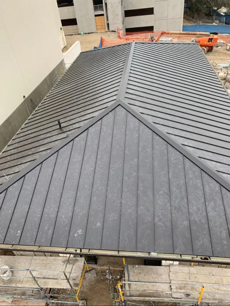 Commercial metal roof construction with crane equipment in Newport